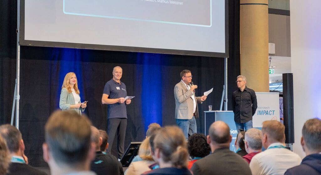 Janine Mehner moderierte die microtech IMPACT. Mit ihr auf der Bühne die microtech-Geschäftsführer (v. l.) Amadeus Kubach, Markus Meißner und Benjamin Bruno © microtech GmbH